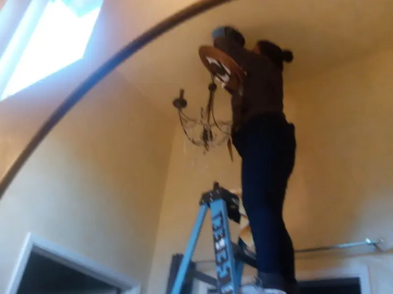 Electrician installing a chandelier in a Grand Bay residence
